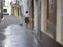 Una vecina de la calle Antonio de la Barrera, limpiando su puerta después de una noche de botellón.